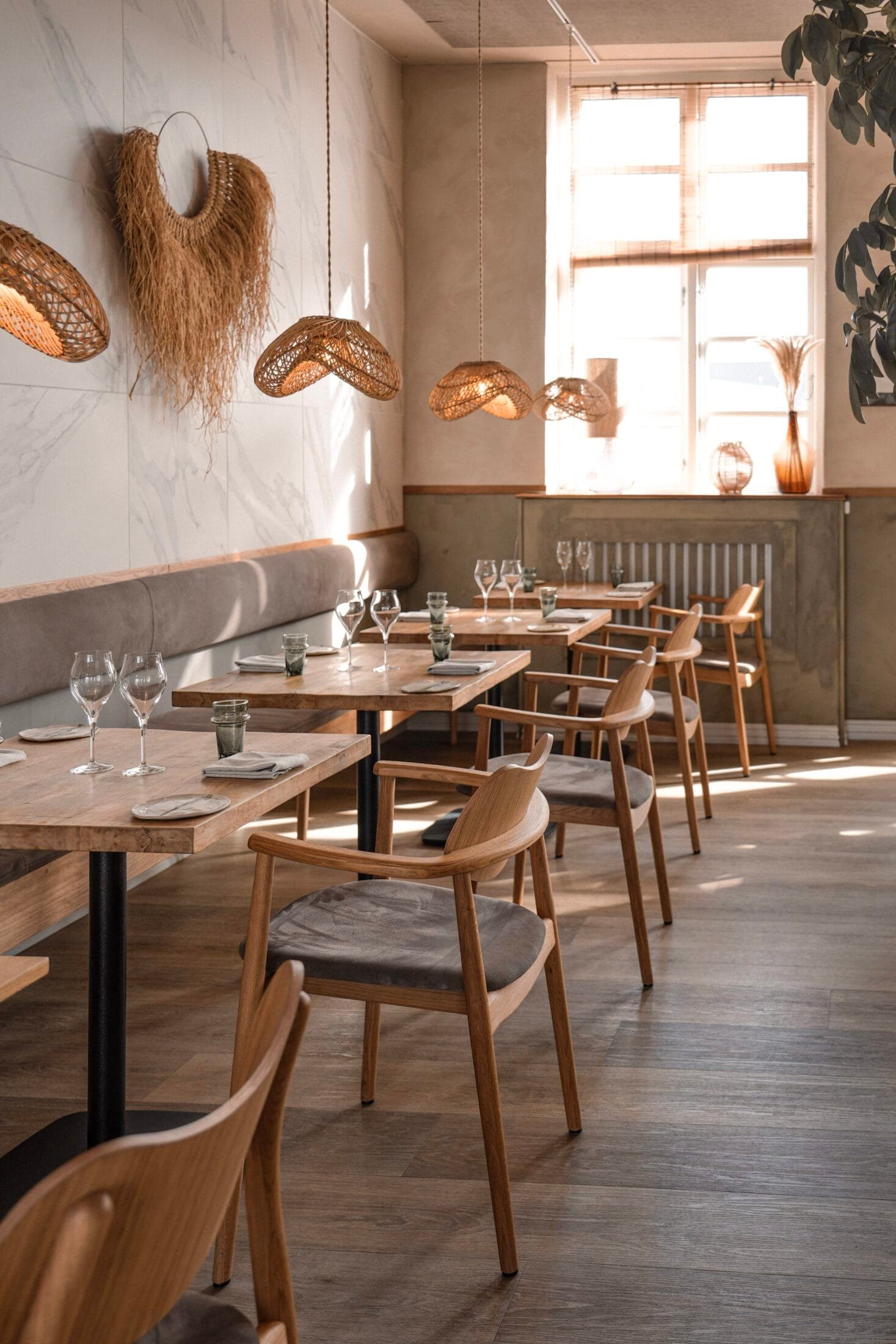 Lys restaurant med træmøbler og flettede pendler
